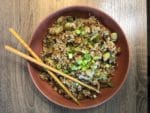 Vegetarian fried rice and chopsticks in a red bowl on wooden surface