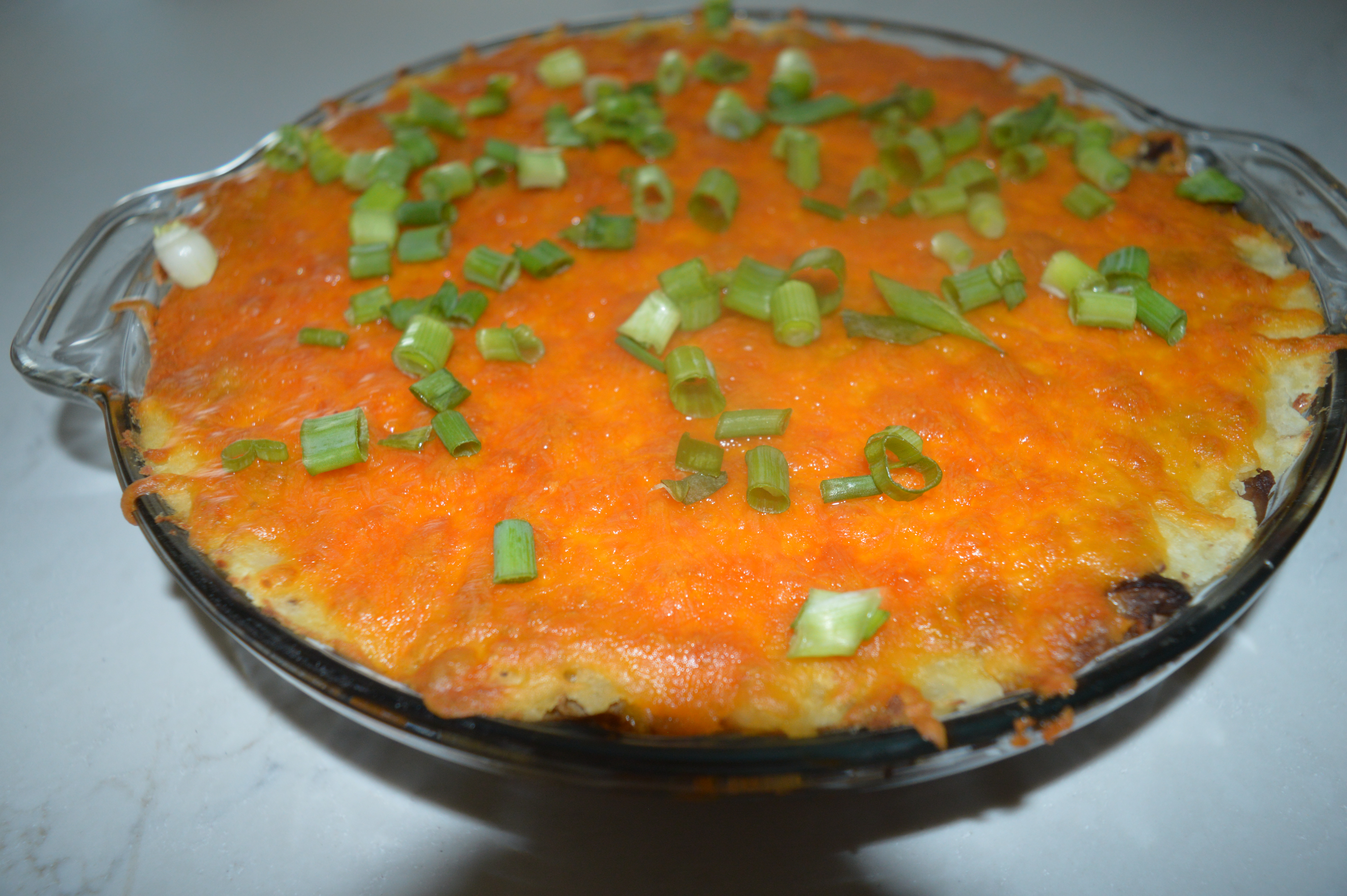 finished tempeh shepherd's pie in a clear pie dish on a white marbled countertop