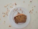 slice of banana bread with pecans on a white plate on a white marbled surface