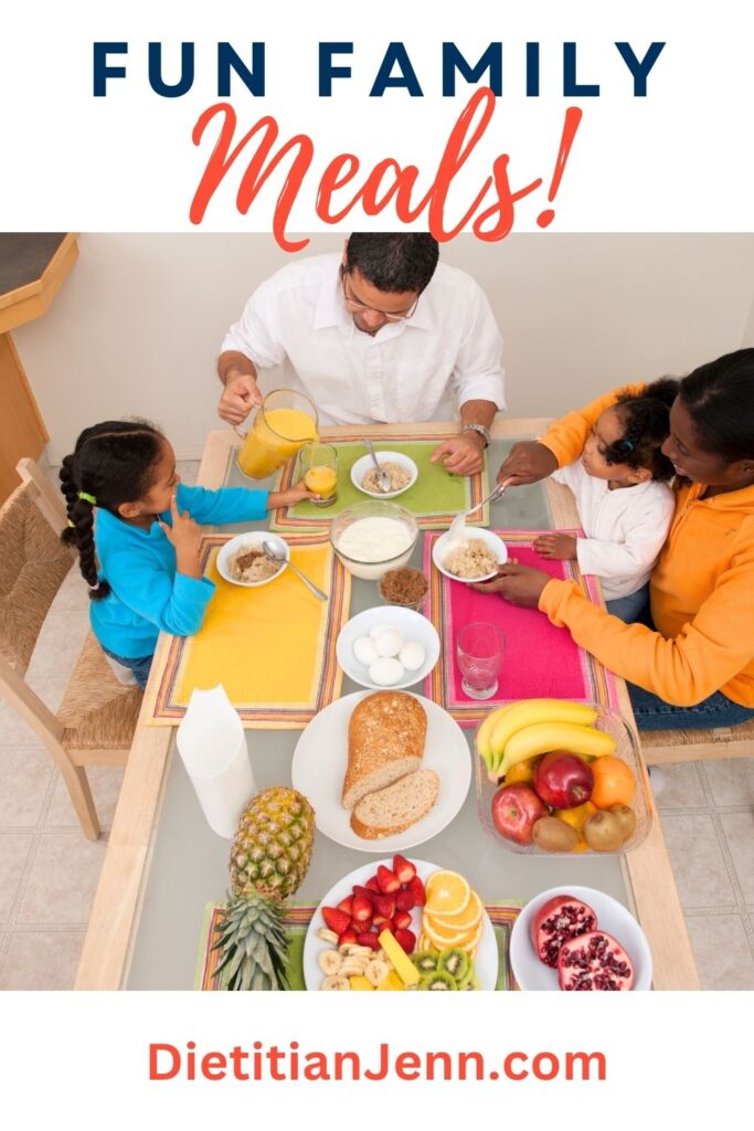 overhead shot down a dining table colorful place mats and plats of fruit, bread, and boiled eggs. A family at the end of the table are eating oatmeal with yogurt and orange juice. Text above reads, "Fun Family Meals!"