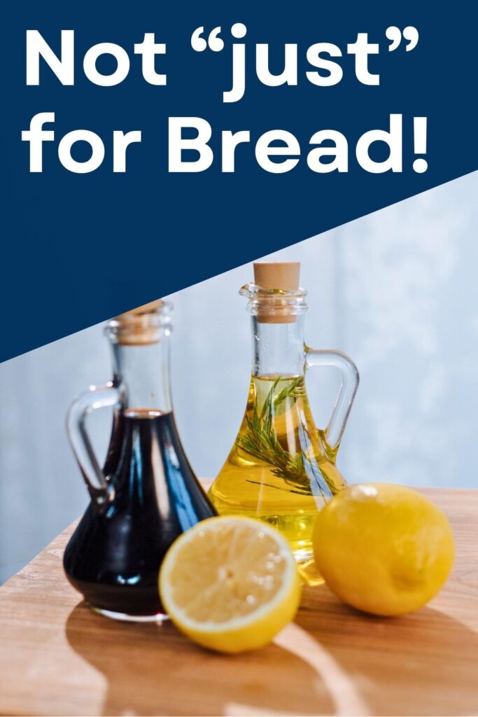 corked glass jars with handles filled with olive oil and balsamic vinegar and a halved lemon on a light wooden surface. text above reads, "Not "just" for bread!"