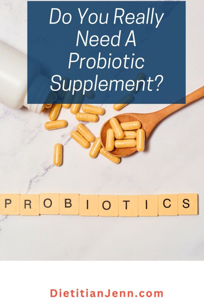 probiotic capsules on and around a wooden spoon on a white marbled surface. Blocks spell out probiotics underneath. Overlaid text reads, "Do you really need a probiotic supplement?