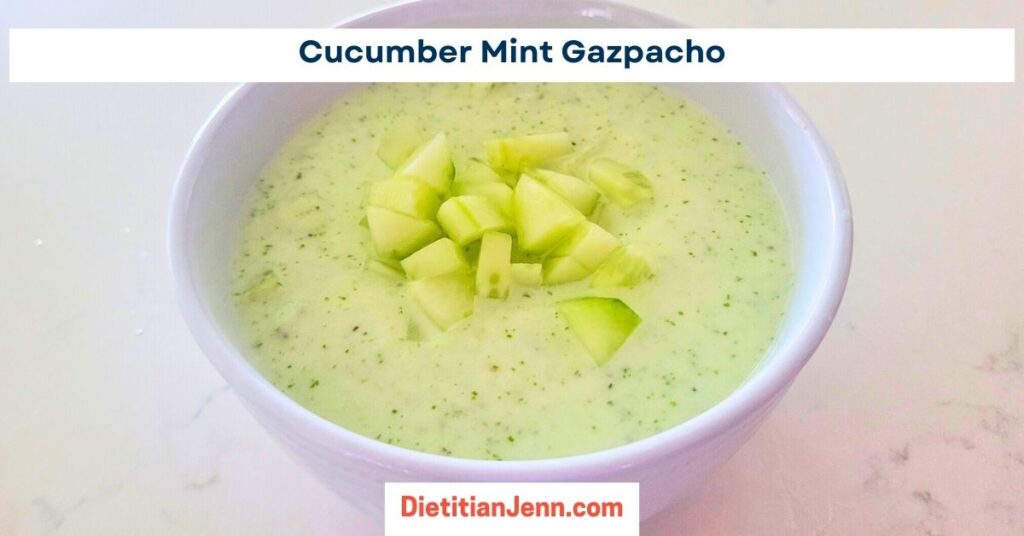cucumber mint gazpacho in a white bowl, garnished with diced cucumbers, on a white marbled surface. text above reads, "Cucumber Mint Gazpacho"