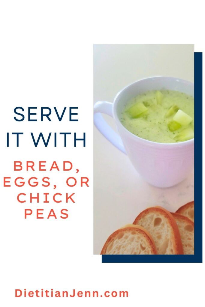 cucumber mint gazpacho in a white mug, garnished with diced cucumbers, on a white marbled surface. sliced bread is next to it. text to the left reads, "Serve it with bread, eggs, or chickpeas"