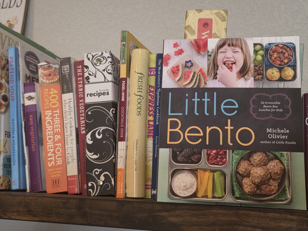 several cookbook spines, with the Little Bento Cookbook facing the front.